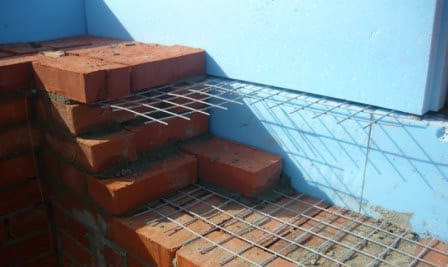 Процесс кладки кирпича на бетонное основание и его армирование