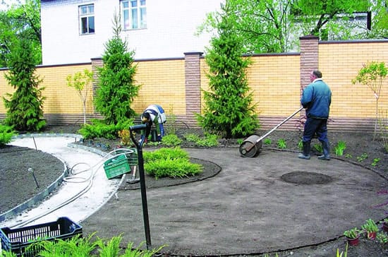 Процесс прокатки почвы для газона специальным катком