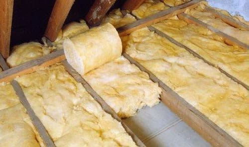 Процесс укладки минеральной ваты в пазы на крыше