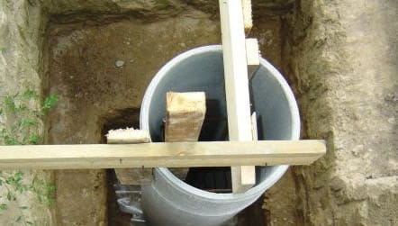 Процесс выравнивания асбестоцементных труб с помощью деревянной опалубки