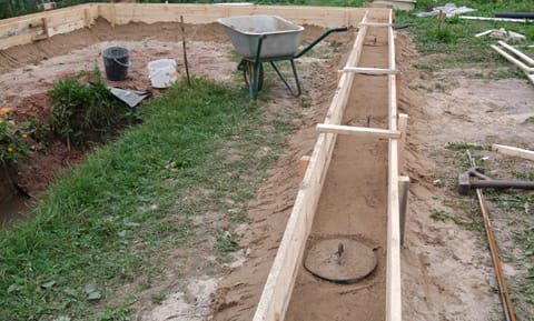 Процесс заливки скважин ростверкового фундамента для гаража