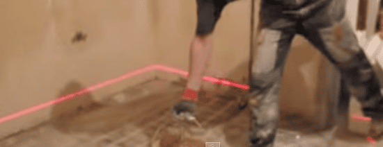Выставляем необходимый уровень заливки пола стяжкой при помощи лазерного строительного уровня.