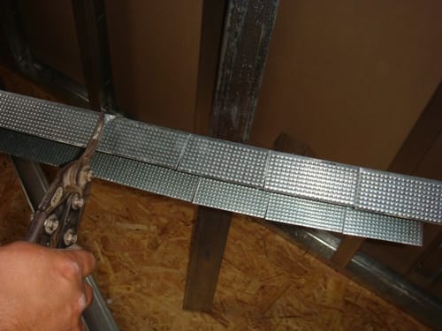Отрезаем ножницами металлический профиль для крепления гипсокартона